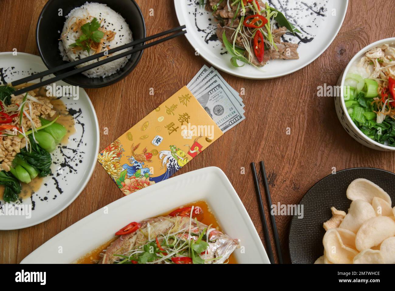 Foods to eat on Lunar New Year’s Eve on the table with golden envelope stuffed with money as a token of good fortune in the New Year. Stock Photo