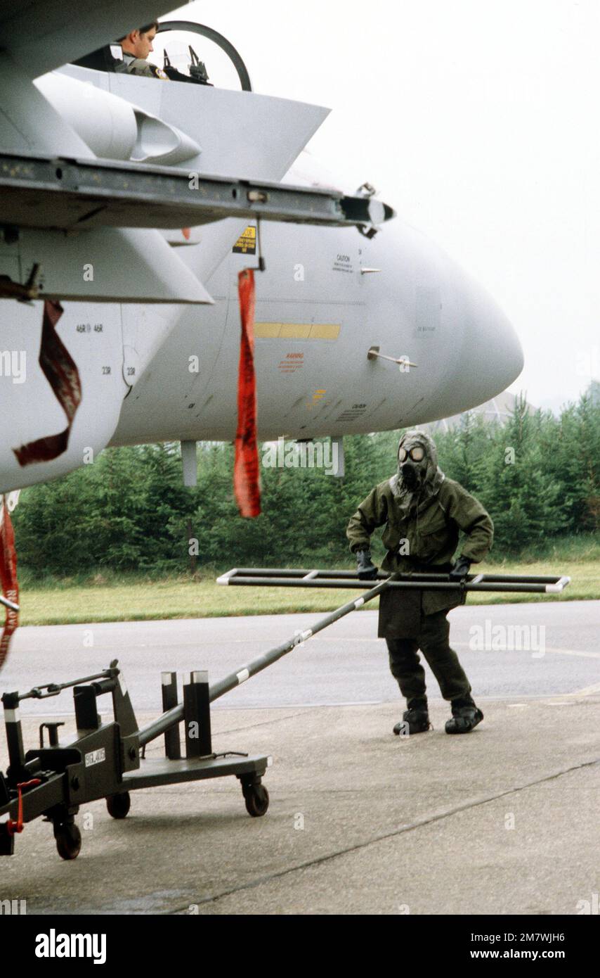 A ground crew member attaches a tow bar to an F15 Eagle aircraft to roll the aircraft out