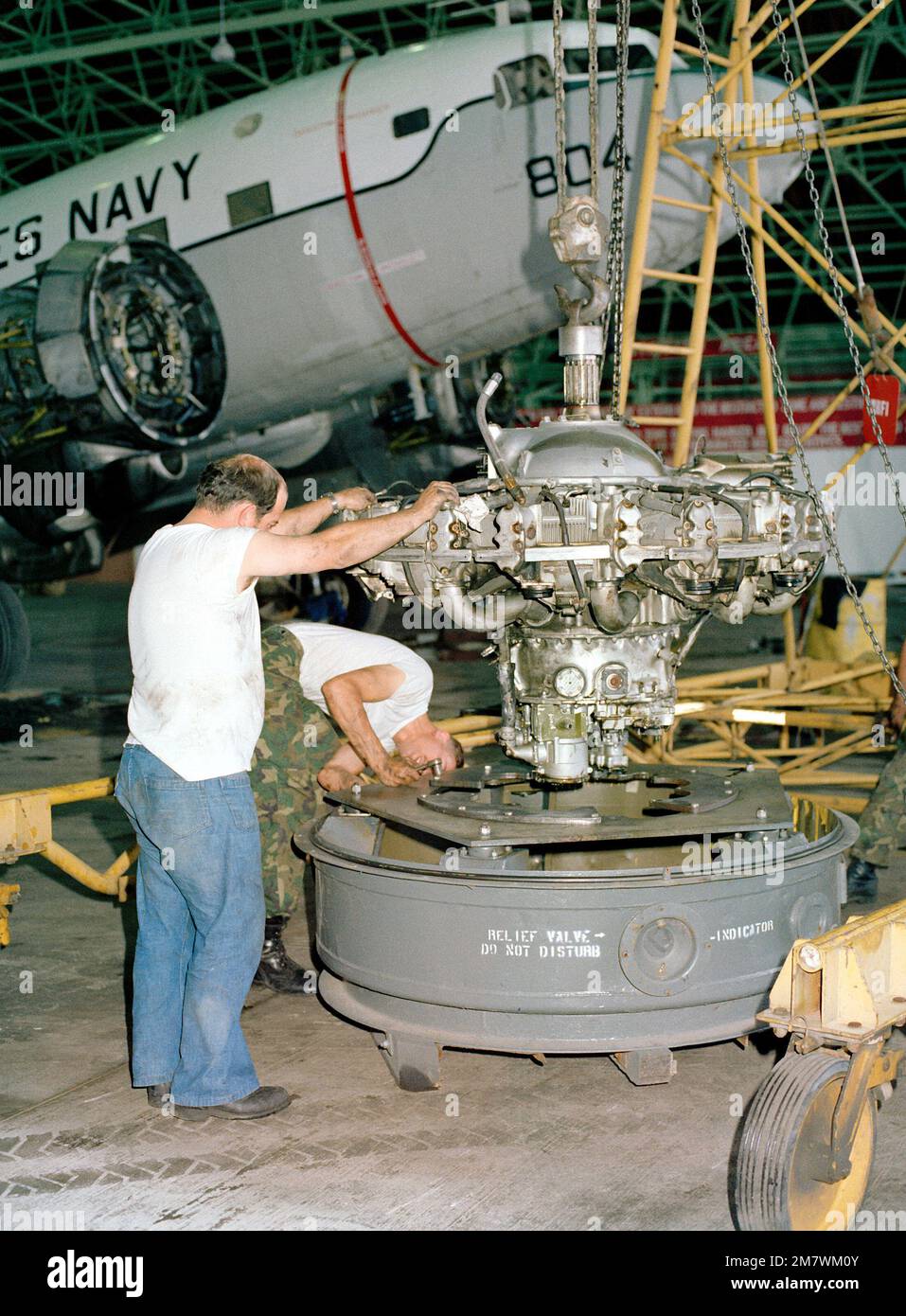 The engine of a C-117 aircraft is lowered into a shipping container to ...