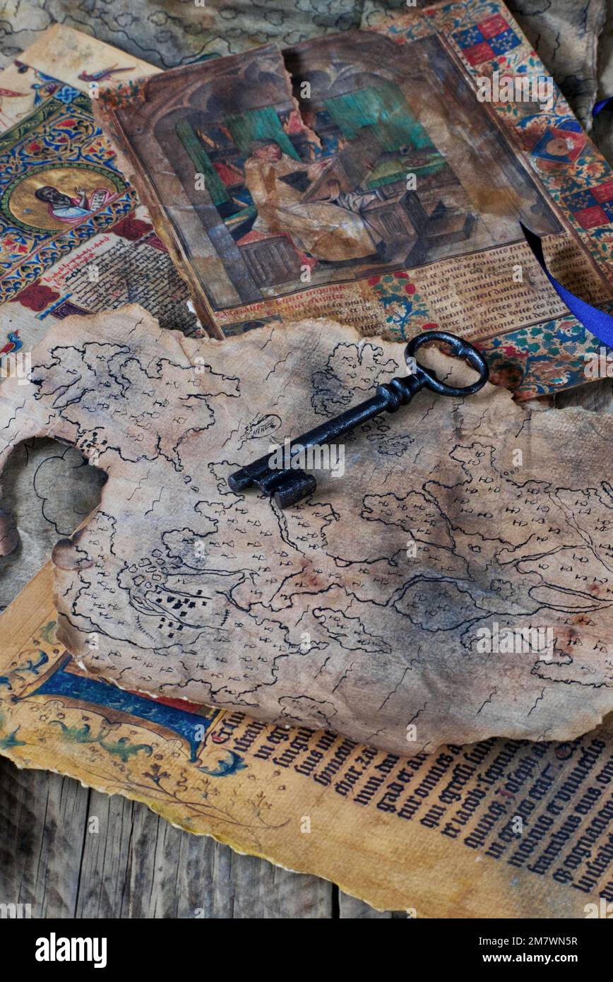 old black key laying on a spread of ancient papers, maps and illuminated texts. mystery book cover style. Stock Photo