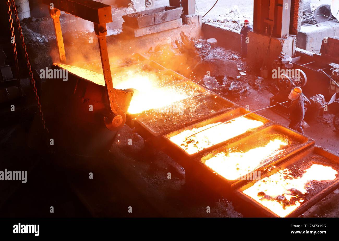 ZHANGYE, CHINA - JANUARY 10, 2023 - A worker injects molten metal silicon into a steel mold at a smelting plant in Zhangye city, Northwest China's Gan Stock Photo