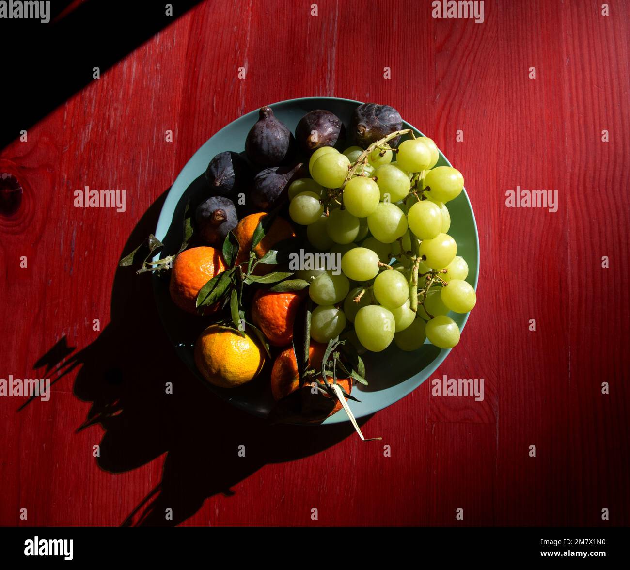Different organic fruits on plate on vintage wooden surface. Game of light and shadows. Mystery meal. Seasonal fruit background. Stock Photo