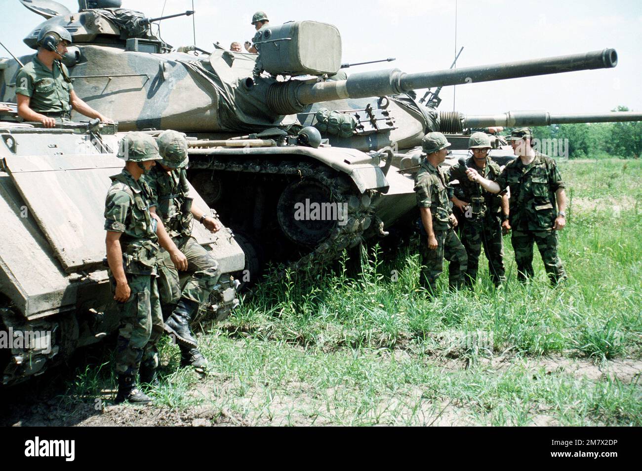 Soldiers participating in Exercise Reforger '82 are interviewed by a member of the U.S. Army Audio-Visual Center television production team in front of an armored personnel carrier and an M-60A1 tank. Subject Operation/Series: REFORGER '82 Base: Fort Riley State: Kansas (KS) Country: United States Of America (USA) Stock Photo