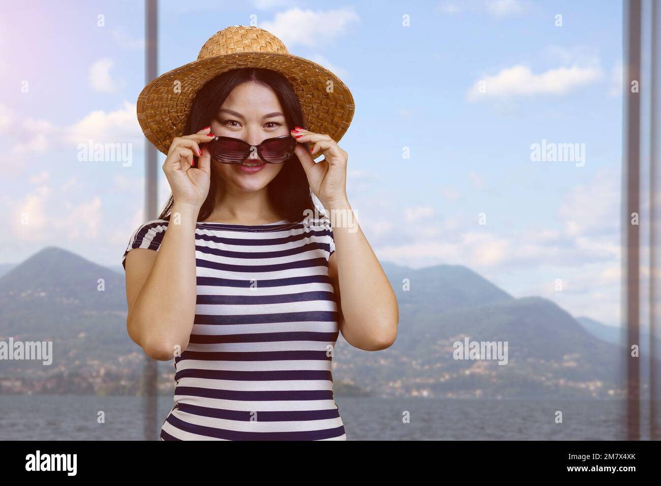 Portrait of a young asian woman in straw hat and striped shirt puts on ...