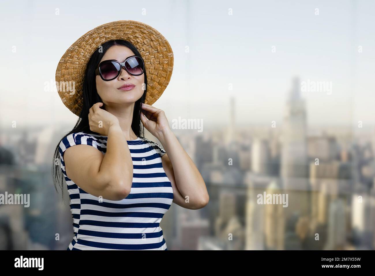 Portrait of a young brunette woman with sunglasses and straw hat ...