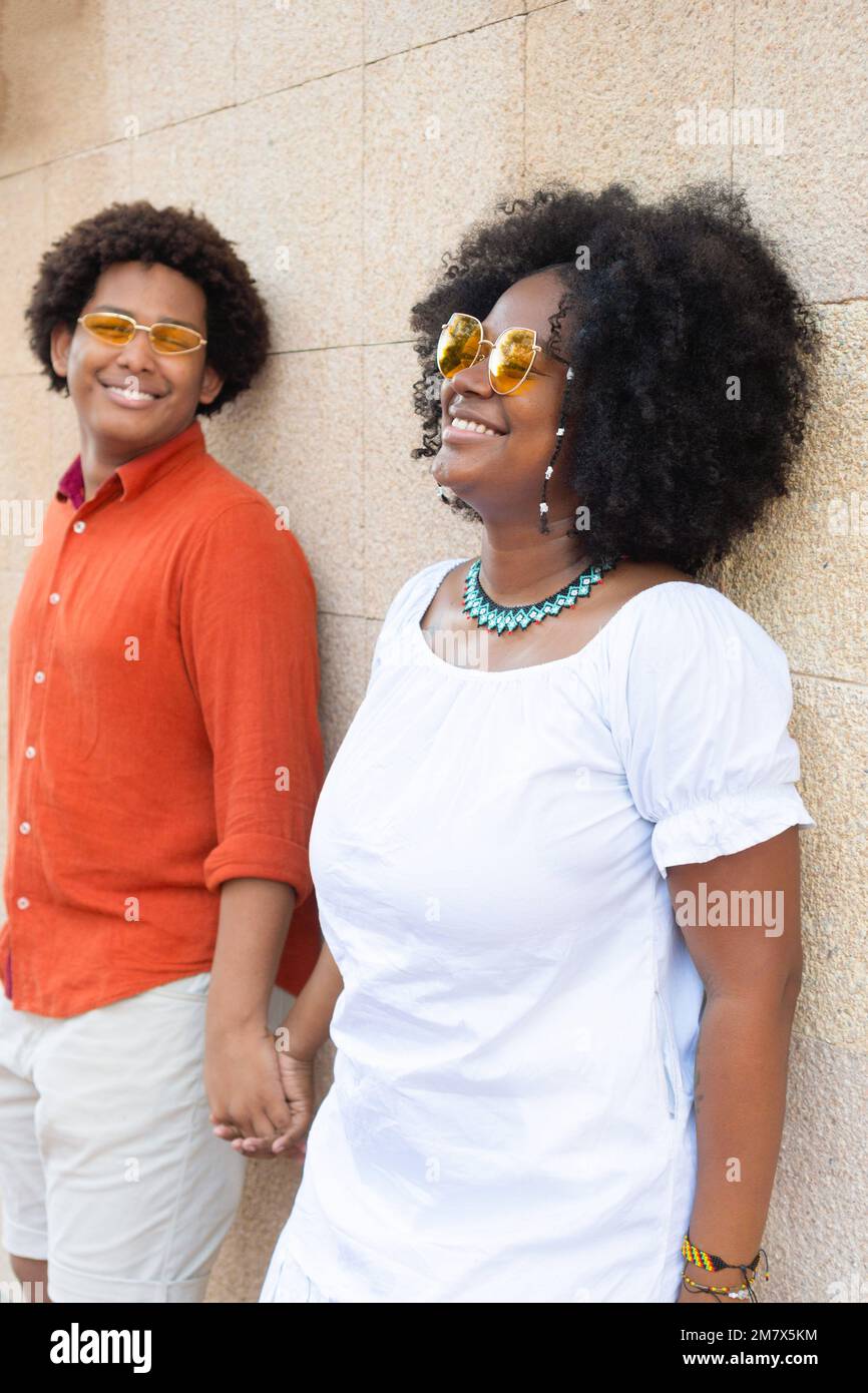 ethnic couple looking sideways against a brick wall. Stock Photo