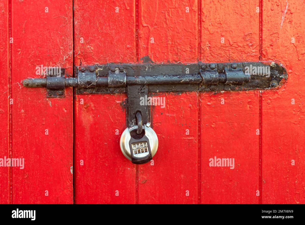 Combination lock locking a steel bolt lock on a double door shed barn