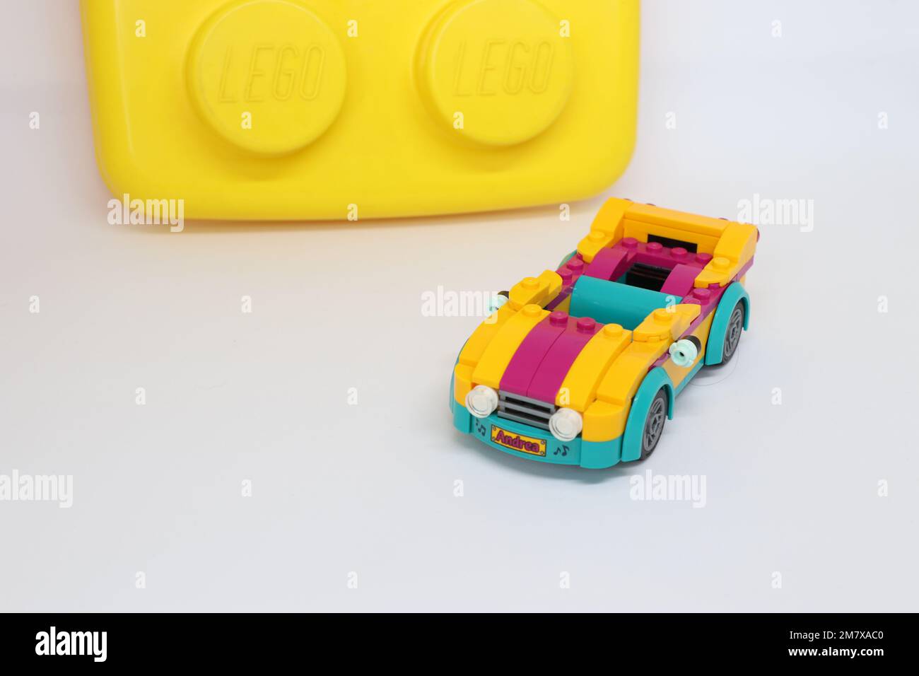 A lego sports car is parked on a white isolated background and a large block in the background. Editorial with copy space Stock Photo