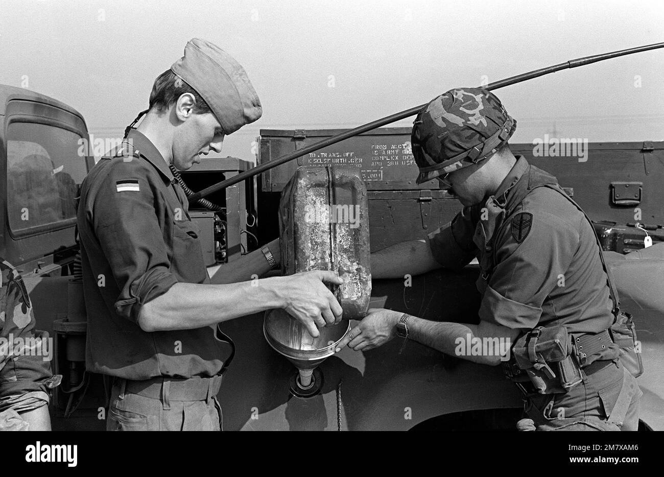 SPECIALIST 4 Angel Guerara, right, 66th Maintenance Company, helps a German soldier refuel a truck at a rest stop. The truck is part of a convoy en route to the exercise area for Carbine Fortress, a NATO exercise held annually in West Germany. Base: Tauberbicbhofsheim Country: West Germany (FRG) Stock Photo