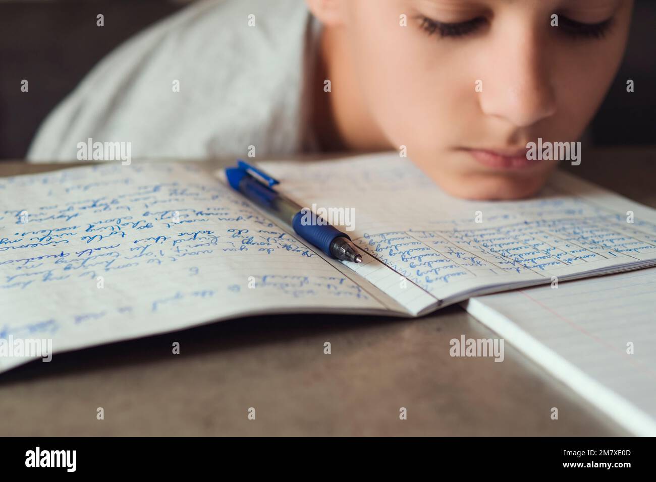 Sad tired boy sitting and looking in to books and notebooks. Education, school, learning difficulties, dyslexia concept Stock Photo