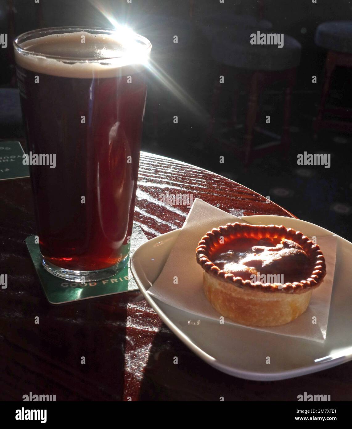 British pie and pint of real ale in a pub, with sunlight through the beer glass, evoking CAMRA pub culture and traditional food. Perfect liquid lunch Stock Photo