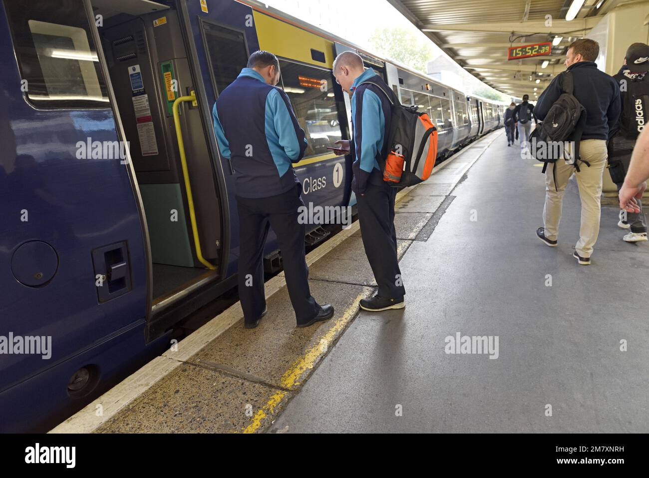 London, England, UK. Two train guards checking their mobile phones at a