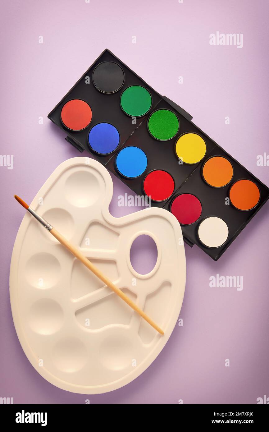 Vertical template with new watercolor paints set, brush and plastic palette. Drawing, arts and hobby backgrounds Stock Photo