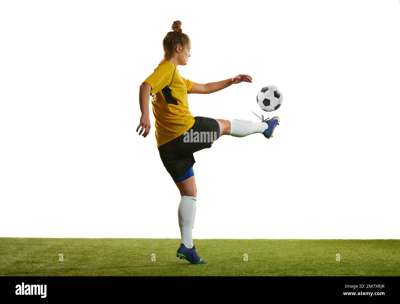 Young woman, professional female football player in motion, training, playing football, soccer isolated over white background Stock Photo