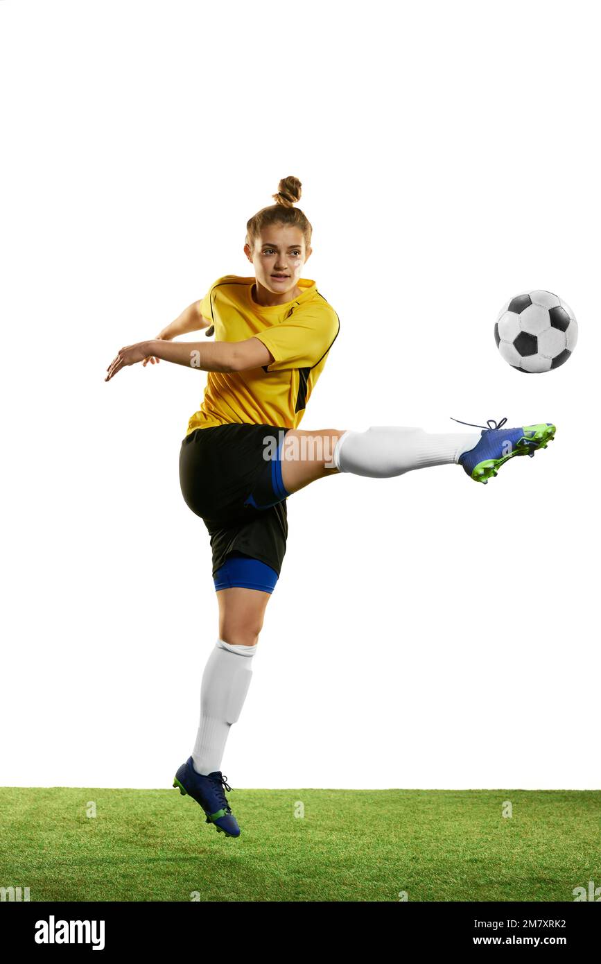 Concentrated young woman, professional female football player in motion, training, playing football, soccer isolated over white background Stock Photo