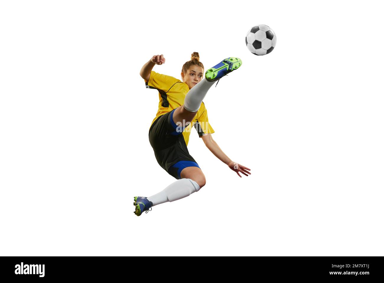 Hitting ball in a jump. Young professional female football, soccer player in motion, training, playing isolated over white background Stock Photo