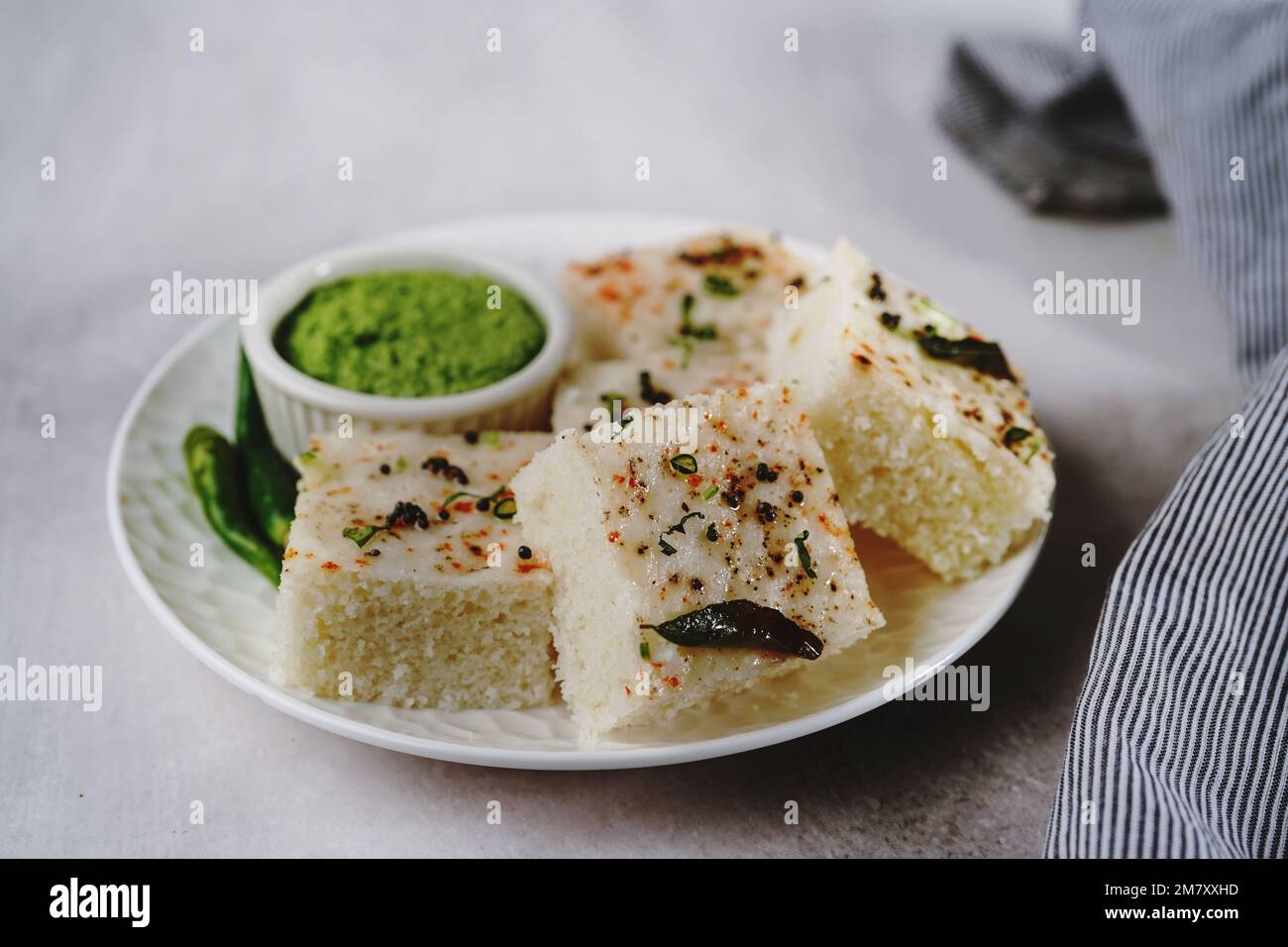 Spongy white dhokla popular Gujarati steamed breakfast with rice or rava served with green