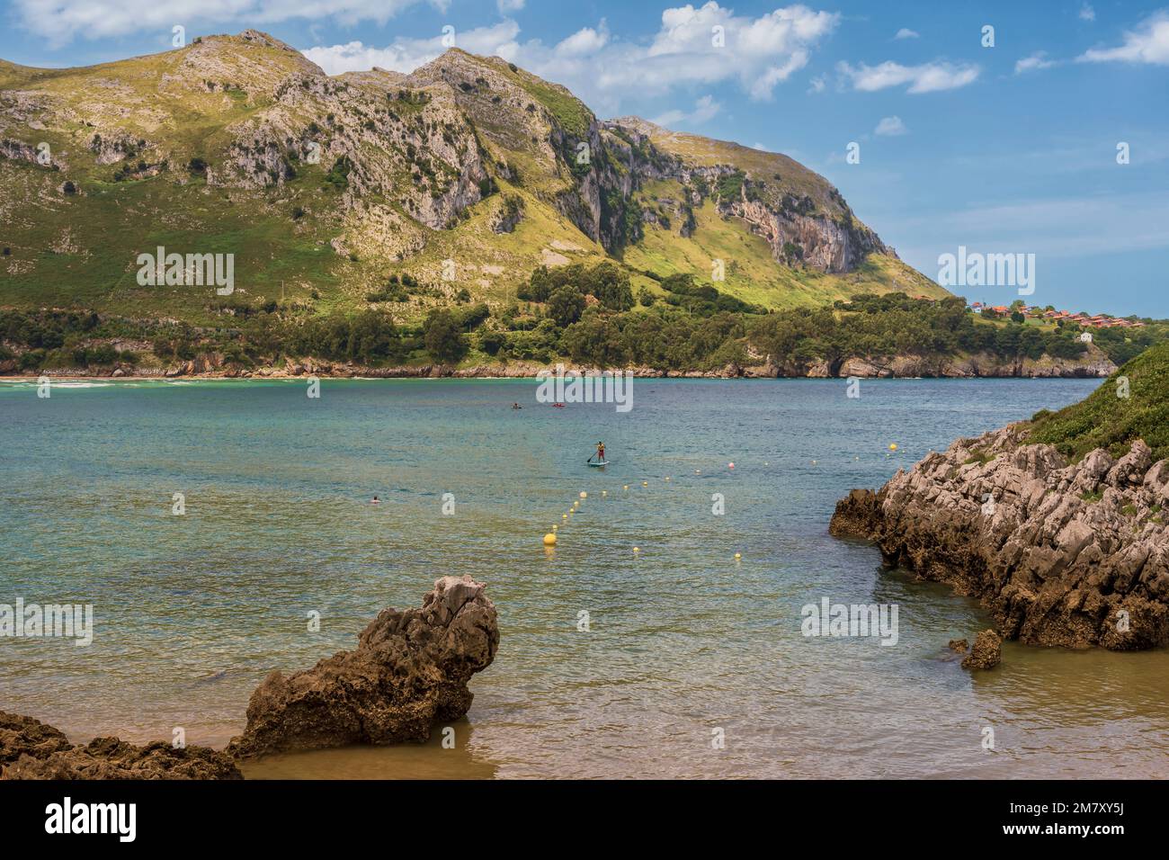 people bathing and canoes sailing, man in paddle surf enjoys calm seas on the beach of Islares, Cantabria, Spain, Europe Stock Photo