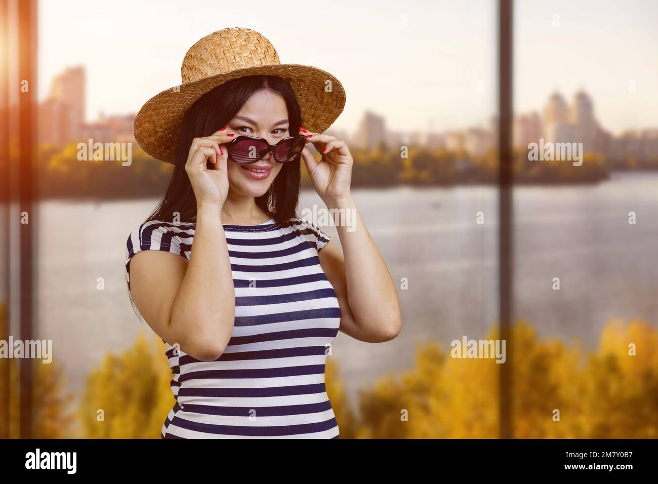 Portrait of a young asian woman in straw hat wearing sunglasses. Window ...