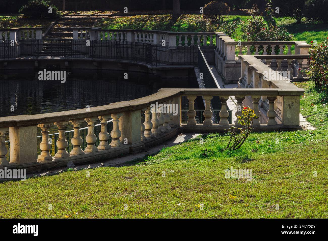 An artificial pond at a city park with grass on the Guastalla Gardens in Milan, Italy during the fall season. Stock Photo
