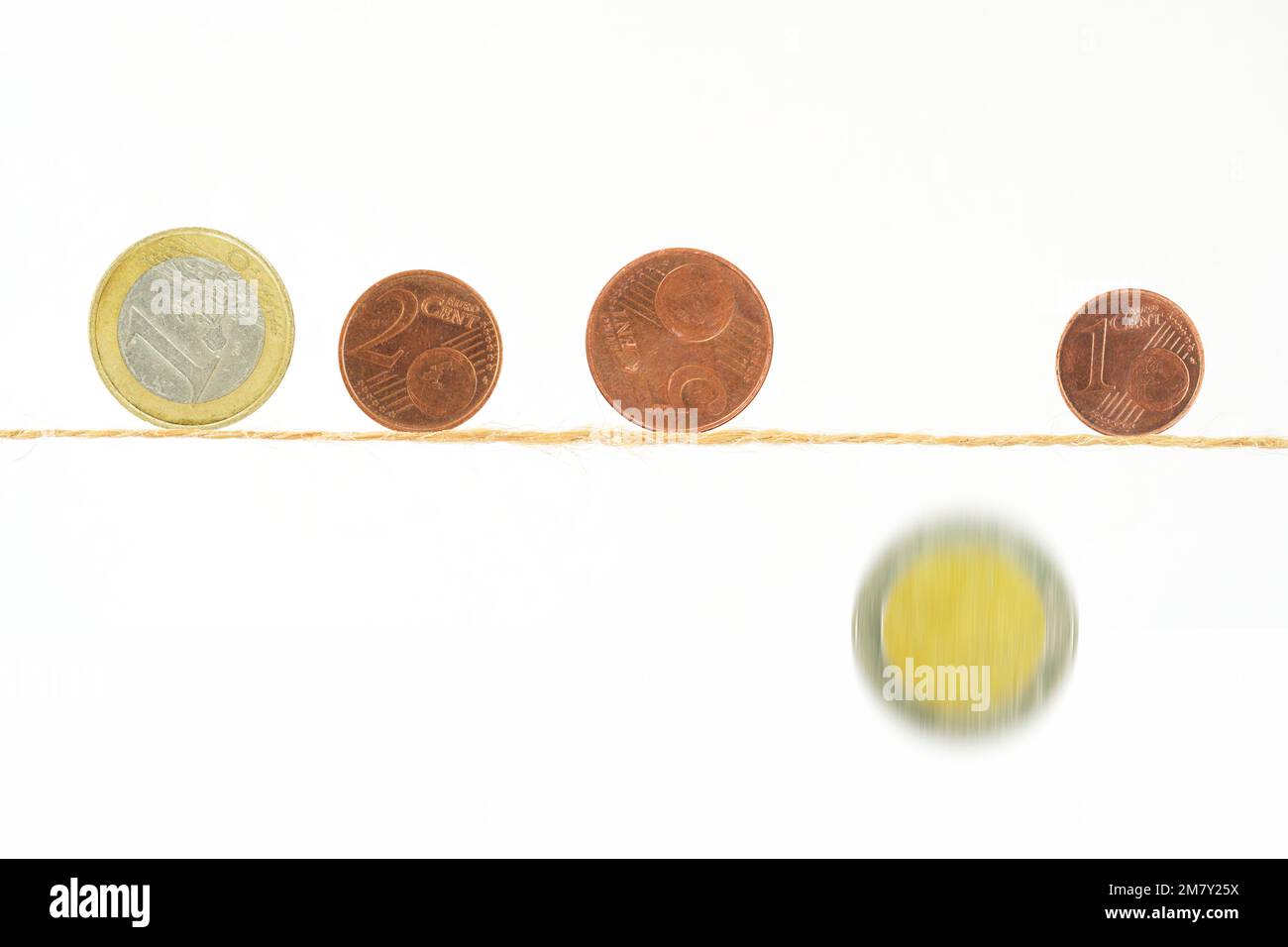 Coins of Euros balancing on a thin rope, one is falling down,financial crisis, inflation,danger of poverty concept. Stock Photo