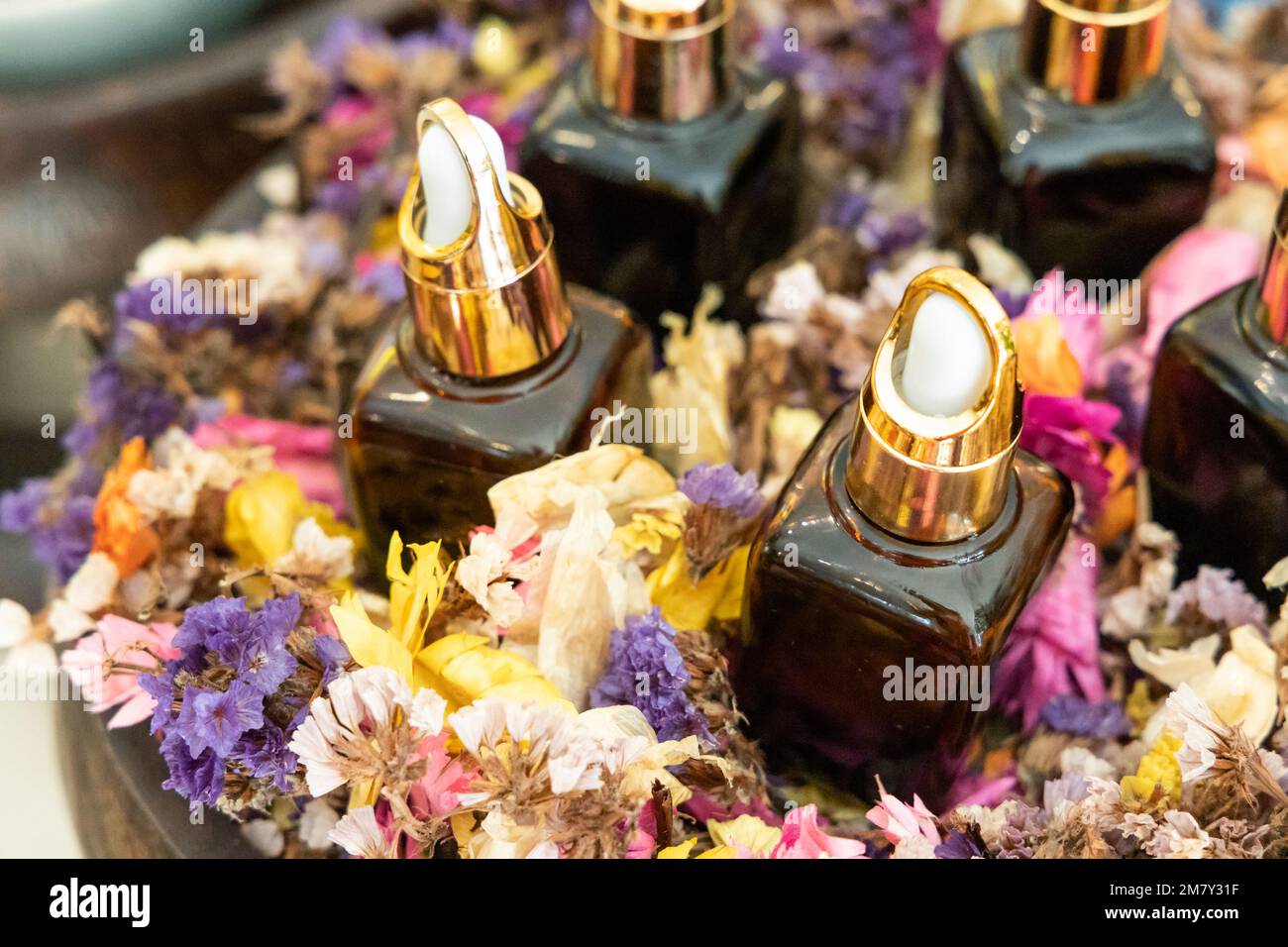Various essential oil dispenser on tray surrounded with rose petals for massage and spa Stock Photo
