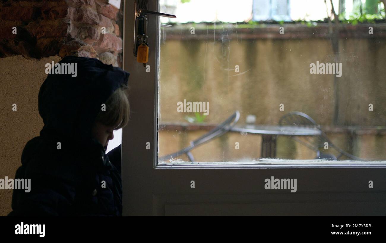 Toddler baby opening front door, stepping out. Child reaching doorknob exiting house Stock Photo