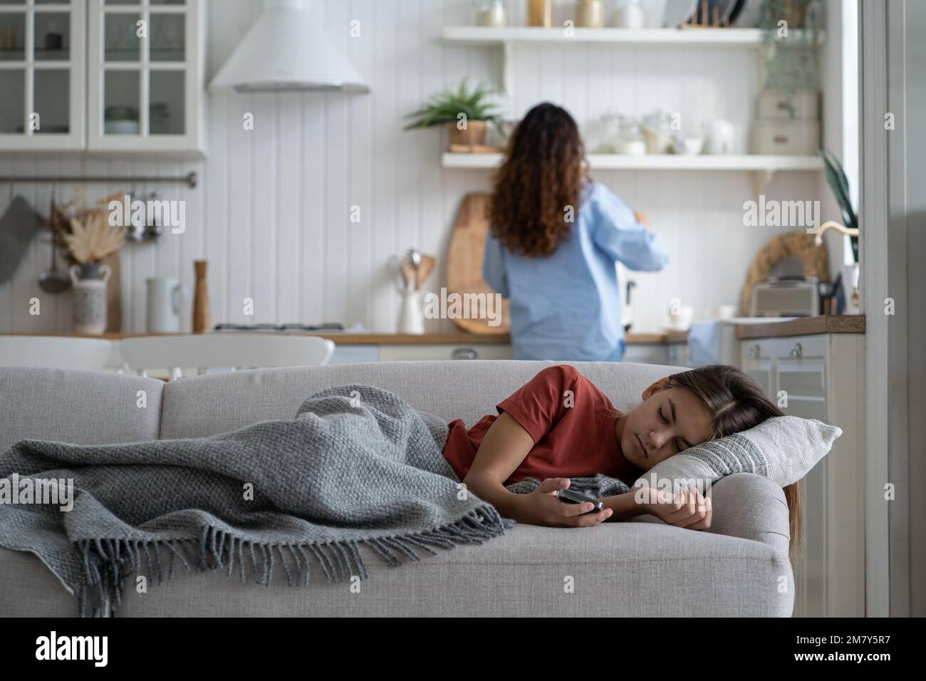Sick unhealthy child girl sleeping under blanket on sofa at home. Seasonal flu and colds