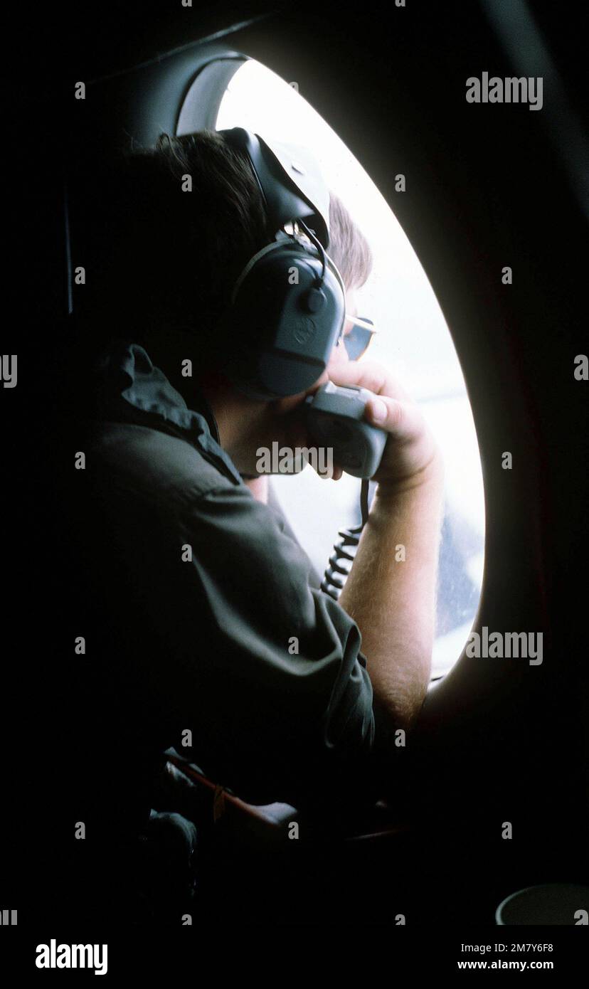 A crewman looks out the observation window of a US Navy P-3 Orion aircraft during Hong Kong Exercise SEARCH AND RESCUE '82. Subject Operation/Series: SEARCH AND RESCUE '82 Country: Hong Kong (HKG) Stock Photo
