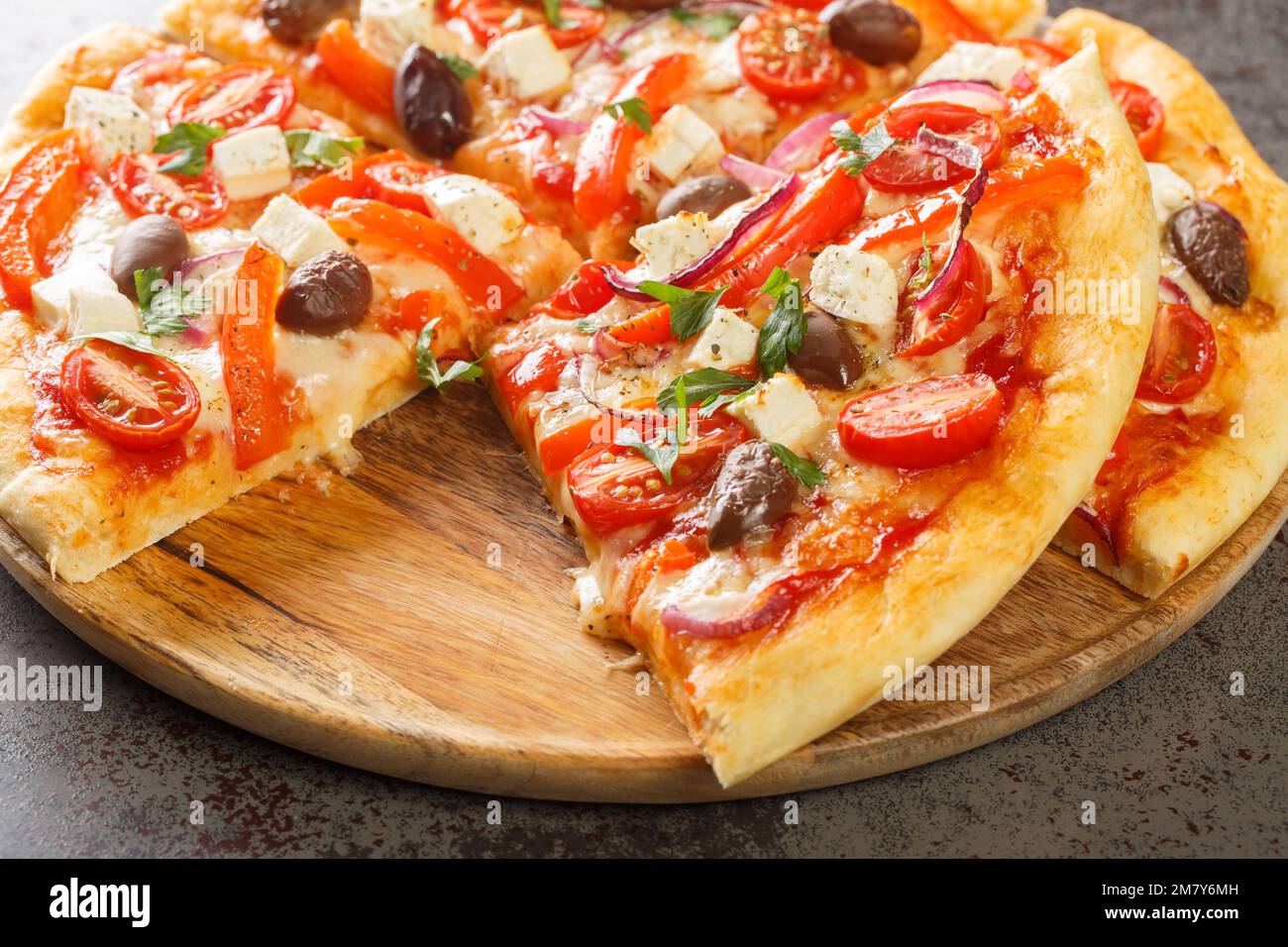 Sliced Greek pizza with olive, tomato, Mozzarella and feta cheese, onions, pepper on wooden board. Horizontal Stock Photo