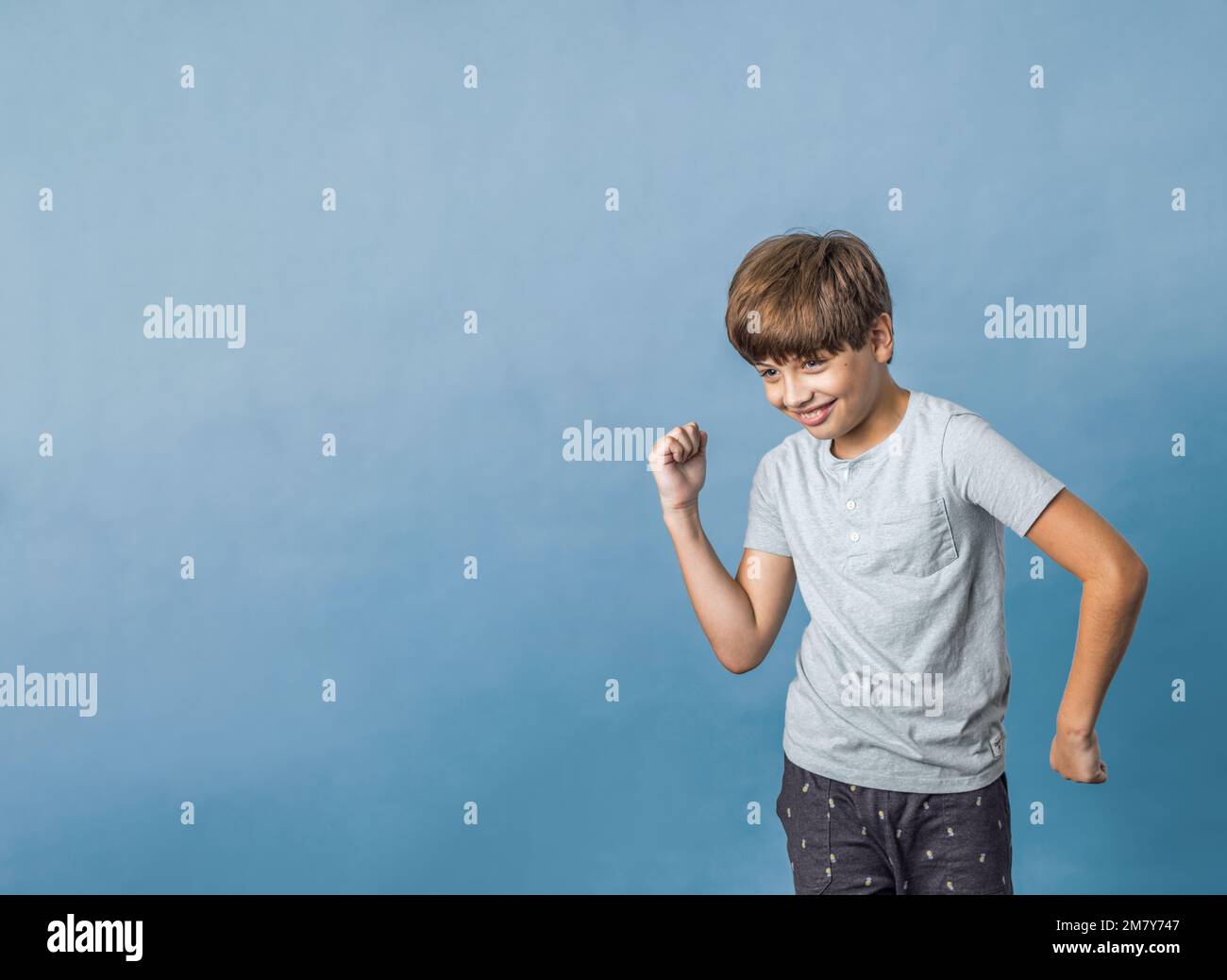 A pre-teen tween boy being silly on a colorful blue background with copy space Stock Photo