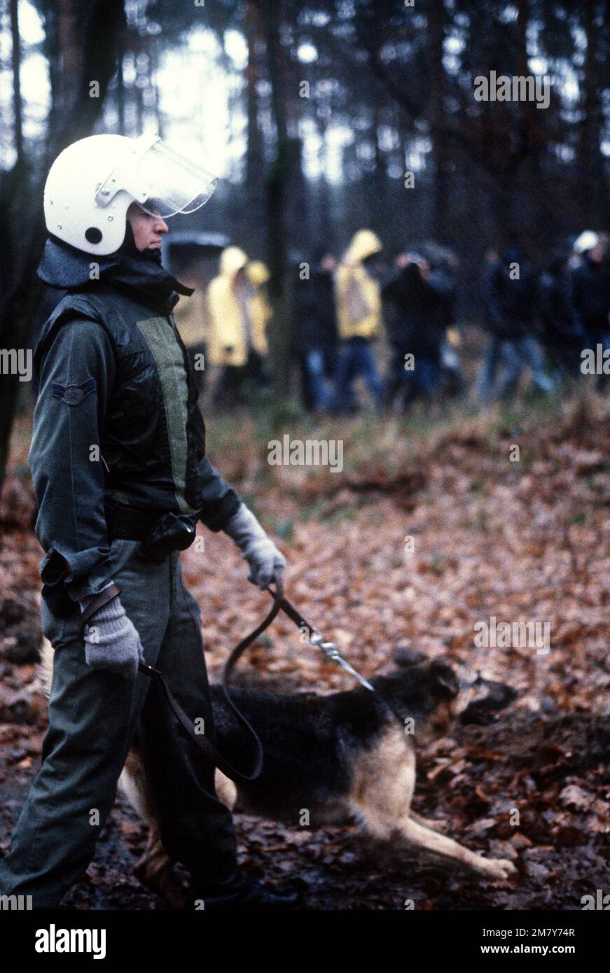AIRMAN 1ST Class Kenneth Liddle and his canine partner move along parallel to protesters marching outside the perimeter fence. The protesters are demonstrating peacefully against NATO's decision to deploy Pershing II and cruise missiles in Western Europe. Base: Rhein-Main Air Base Country: Deutschland / Germany (DEU) Stock Photo