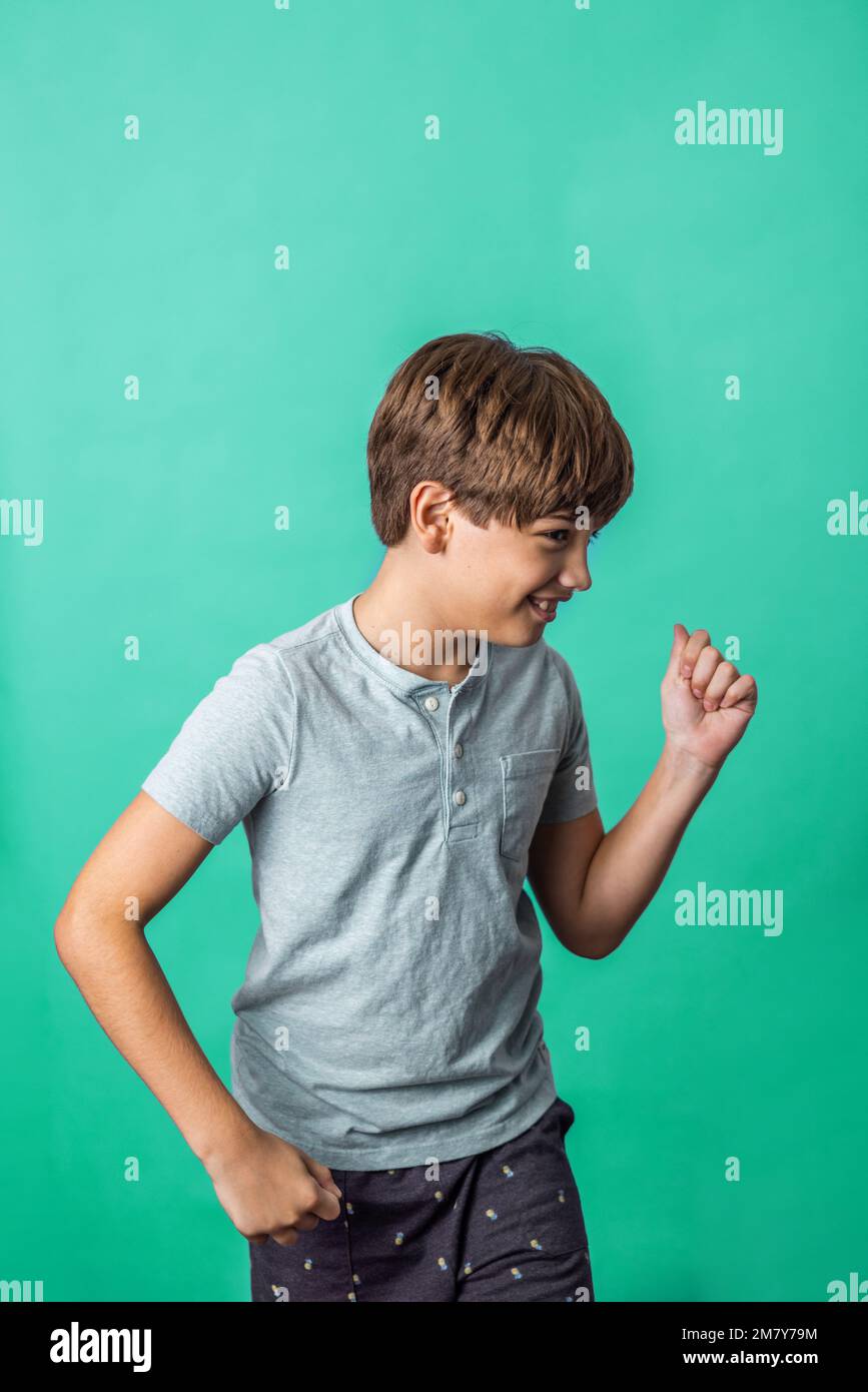A pre-teen tween boy being silly on a colorful green background with copy space Stock Photo