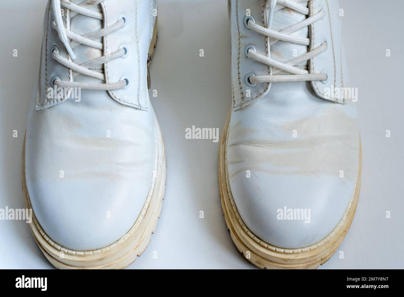 White leather boots with yellow stains on white background Stock Photo