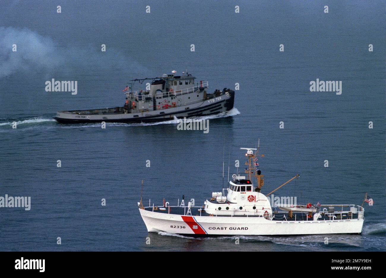 A port view of the Point class patrol boat USCG GLASS (WPB 82336) as it passes the starboard side of the harbor tug ARCATA (YTB 768). Country: Unknown Stock Photo