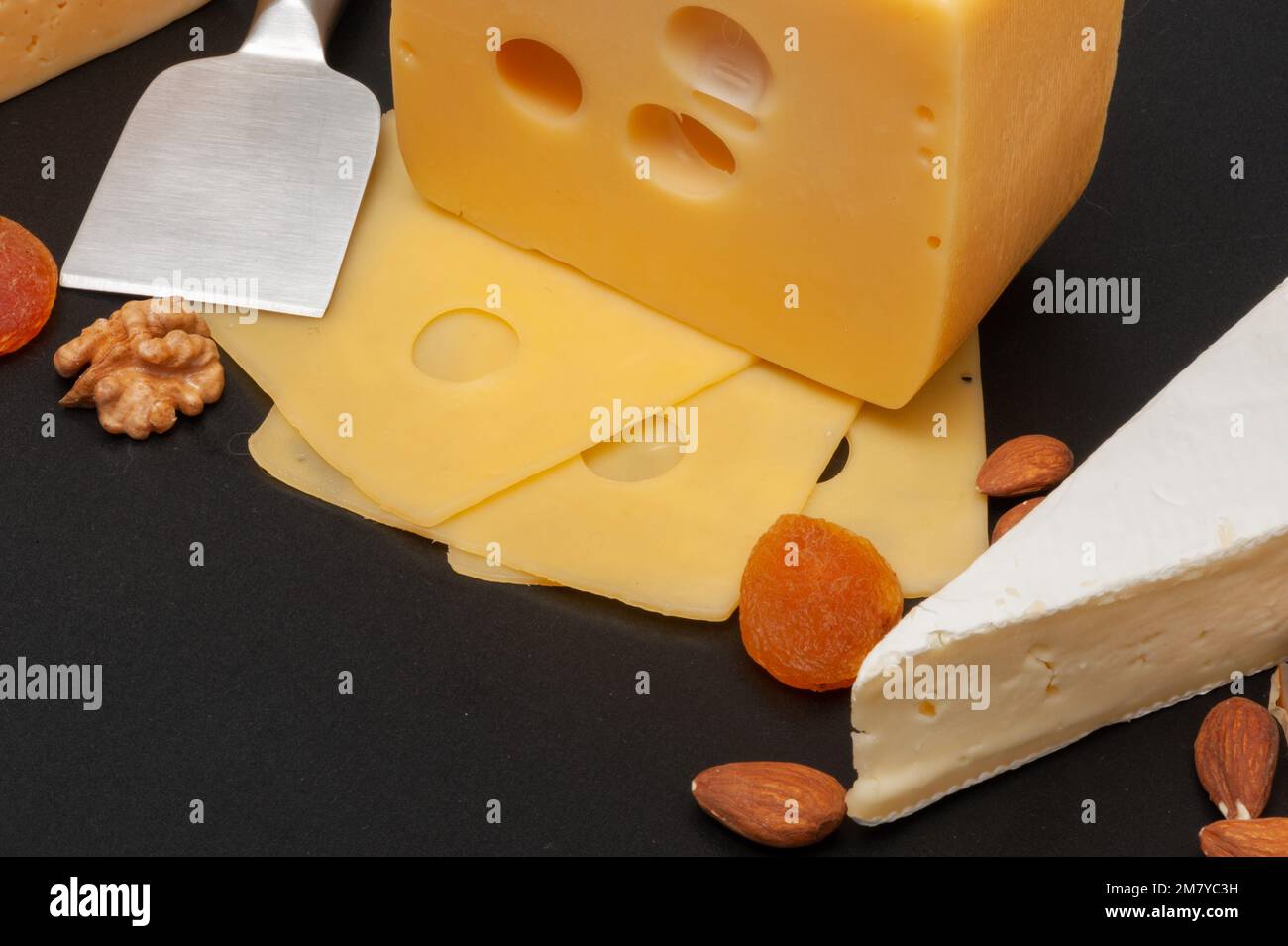 Different types of cheese on a wooden board decorated with grapes