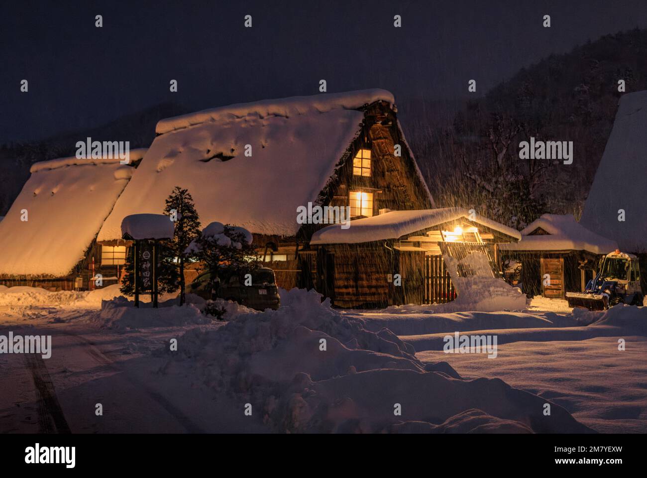 Snow falls on traditional Japanese gassho-zukuri house at night Stock Photo