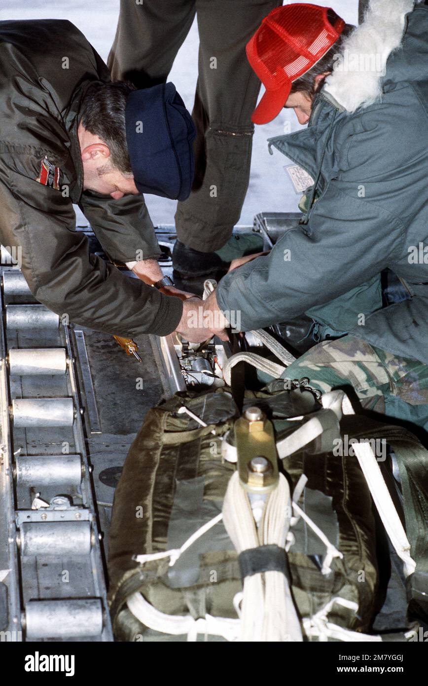 Soldiers and airmen work together to prepare a load of munitions to be dropped using the Low Altitude Parachute Extraction System (LAPES) during exercise Brim Frost. Subject Operation/Series: BRIM FROST '83 Base: Elmendorf Air Force Base State: Alaska (AK) Country: United States Of America (USA) Stock Photo