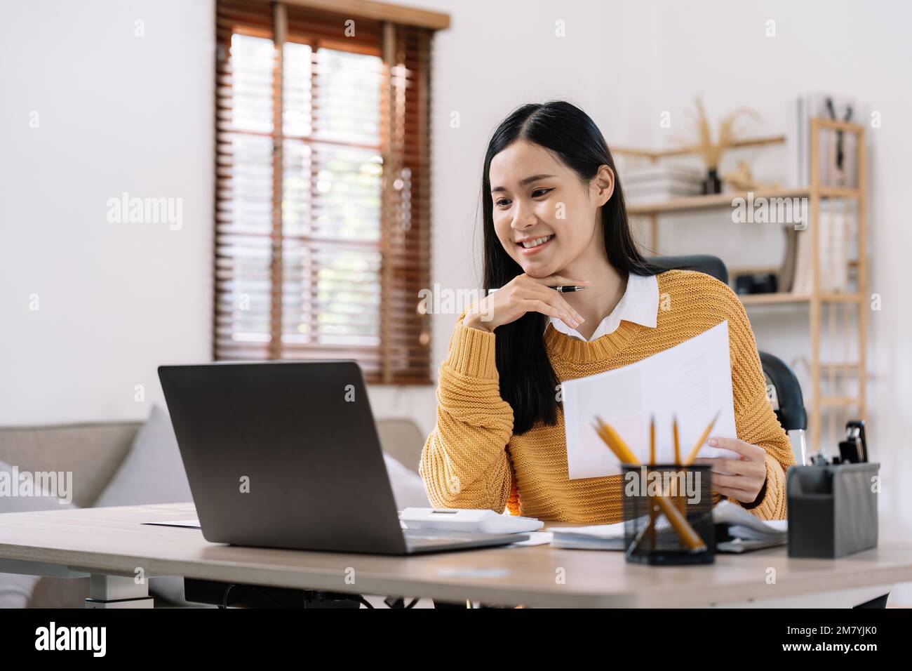 Beautiful young smiling asian businesswoman working on laptop and ...