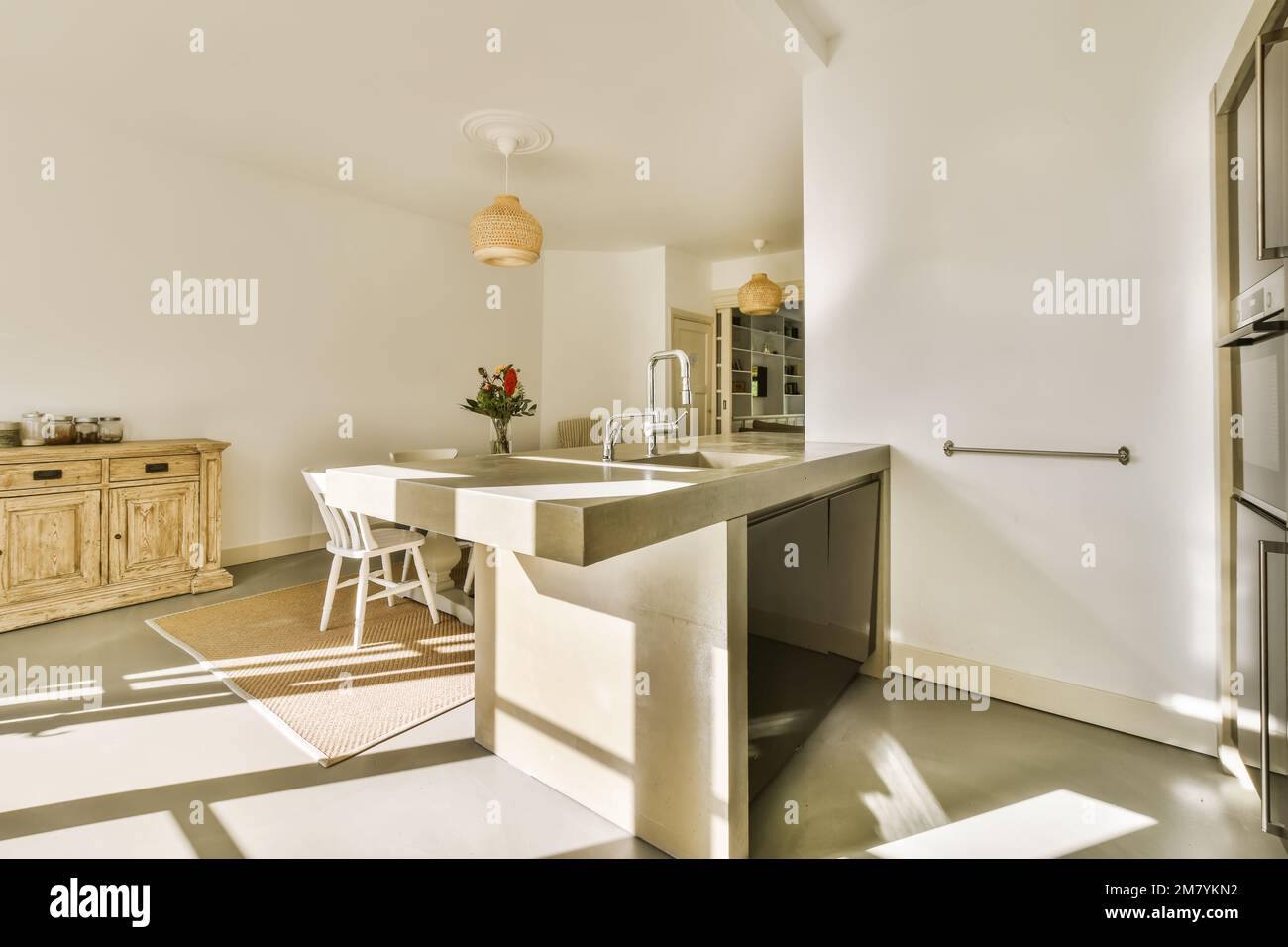 a kitchen and dining area in a house with sunlight shining through the windows on the wall to the room's floor Stock Photo