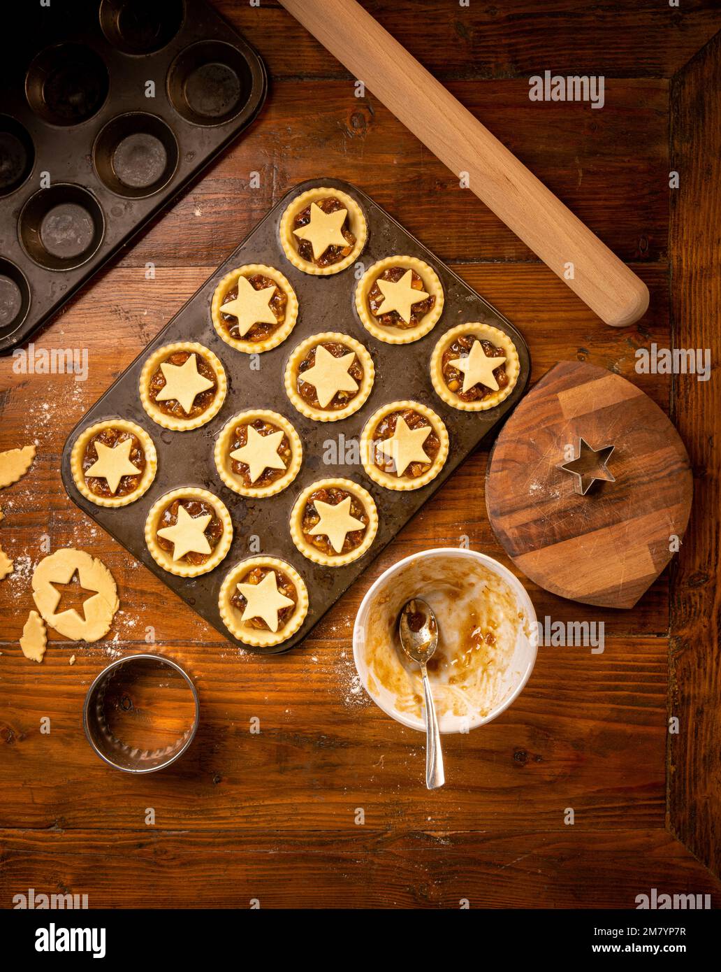 Flat lay of metal bun tin containing star topped mince pies ready for baking. Christmas baking. Stock Photo