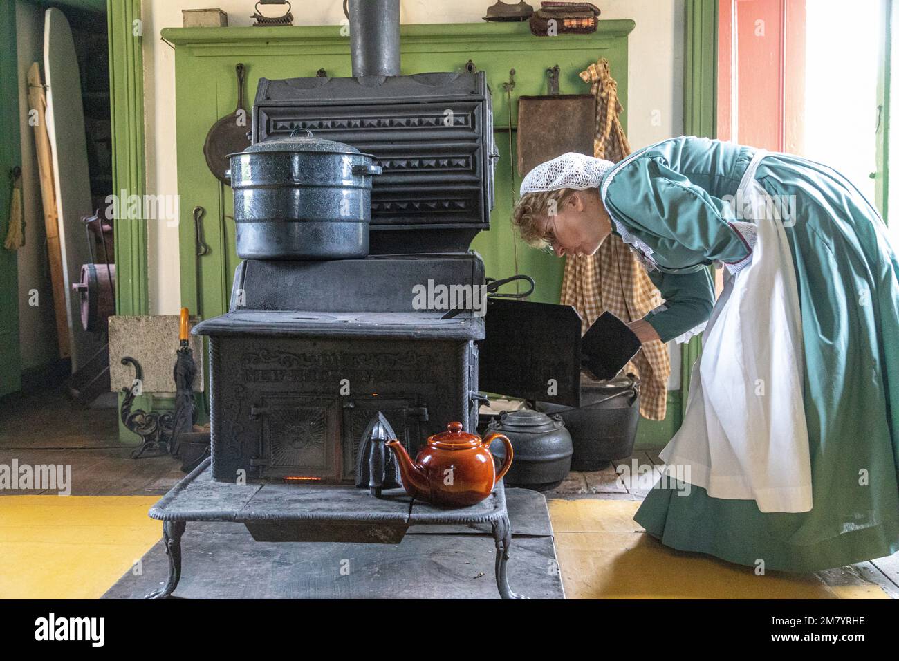 WOMAN AT THE STOVE, PERLEY FARM, KINGS LANDING, HISTORIC ANGLOPHONE VILLAGE, PRINCE WILLIAM PARISH, FREDERICTON, NEW BRUNSWICK, CANADA, NORTH AMERICA Stock Photo