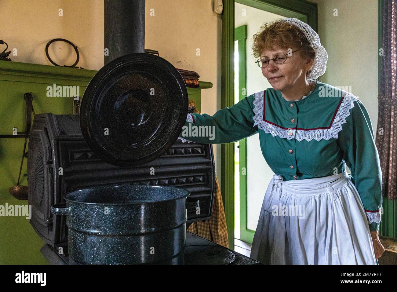 WOMAN AT THE STOVE, PERLEY FARM, KINGS LANDING, HISTORIC ANGLOPHONE VILLAGE, PRINCE WILLIAM PARISH, FREDERICTON, NEW BRUNSWICK, CANADA, NORTH AMERICA Stock Photo