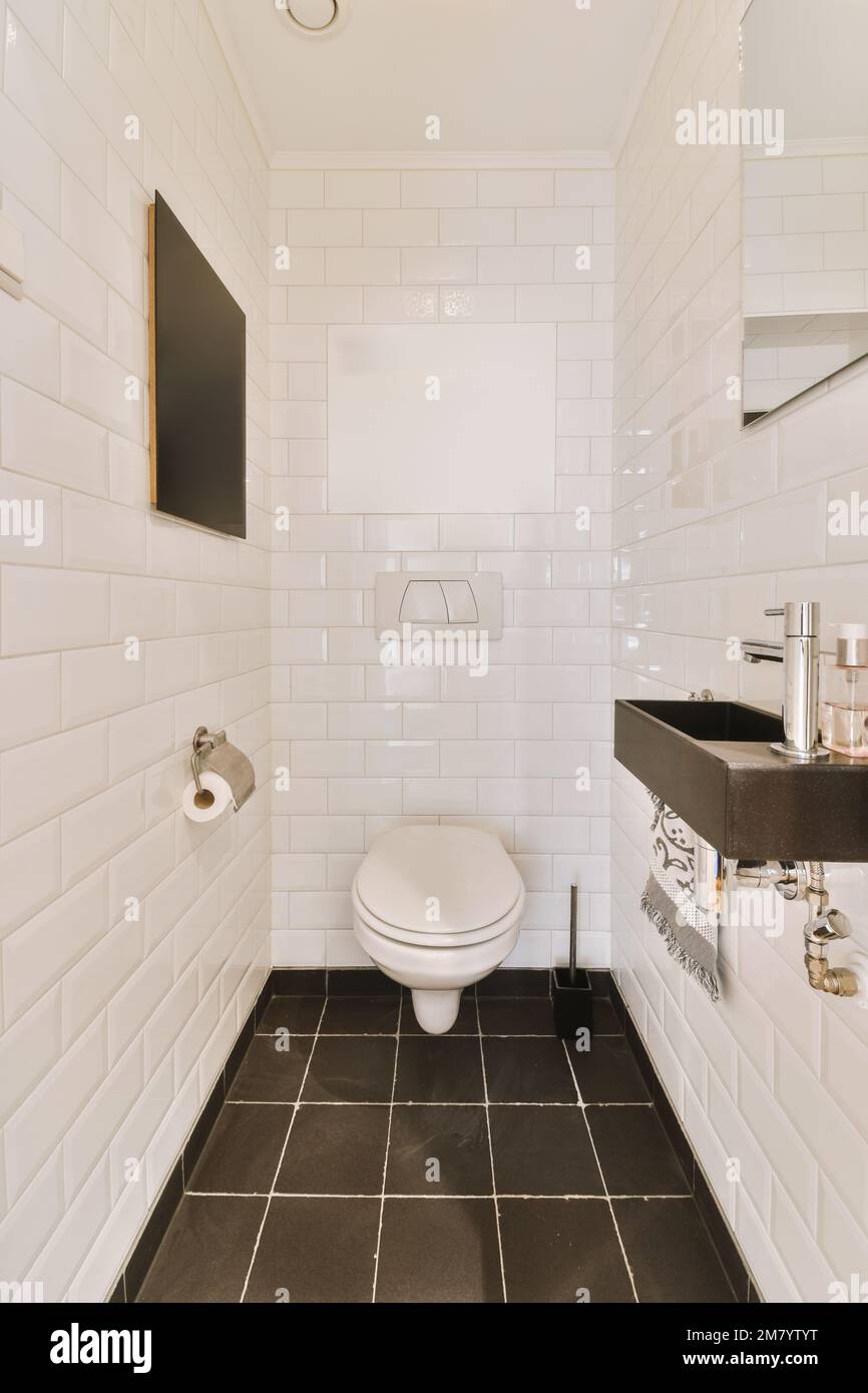a bathroom with black and white tiles on the floor, sink, toilet, and mirror in it's corner Stock Photo