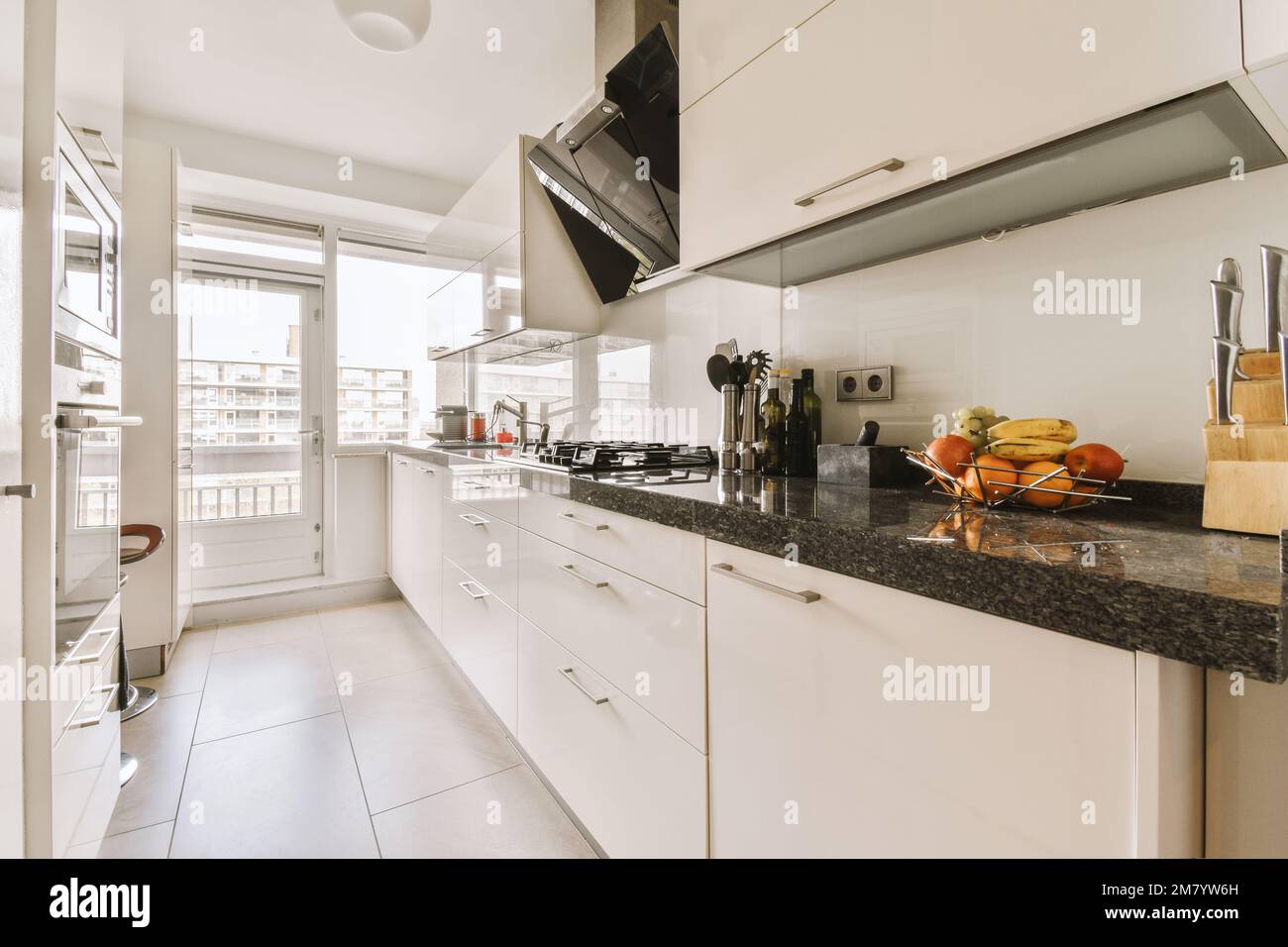 a kitchen with white cabinets and black counter tops in front of the ...