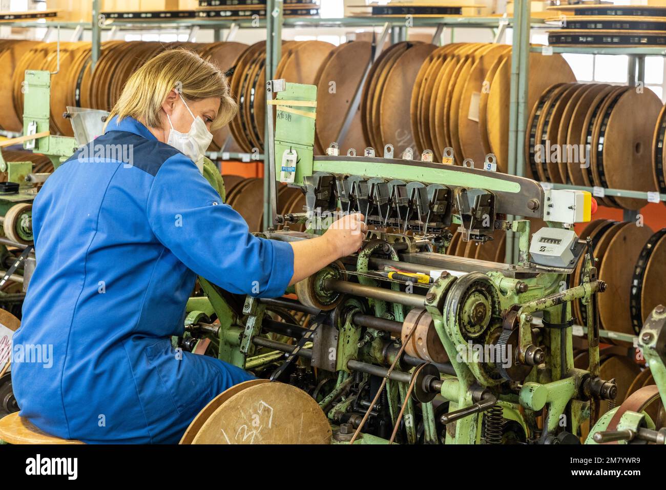 WORKER THREADING NEEDLES ON THE BOBBINS OF FABRIC BEFORE THE FINAL