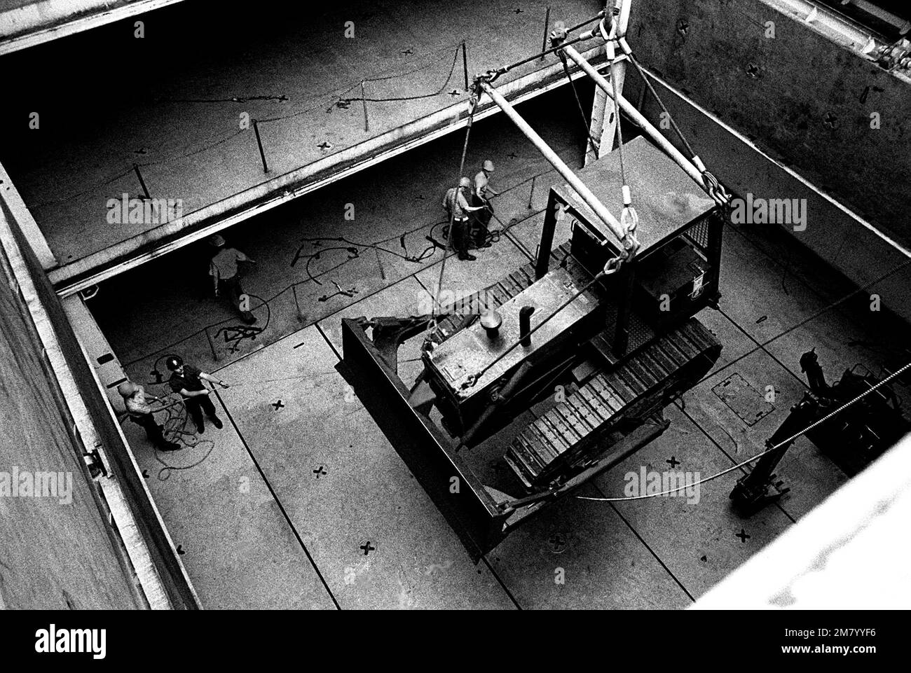 Seabees load heavy equipment aboard the amphibious cargo ship USS