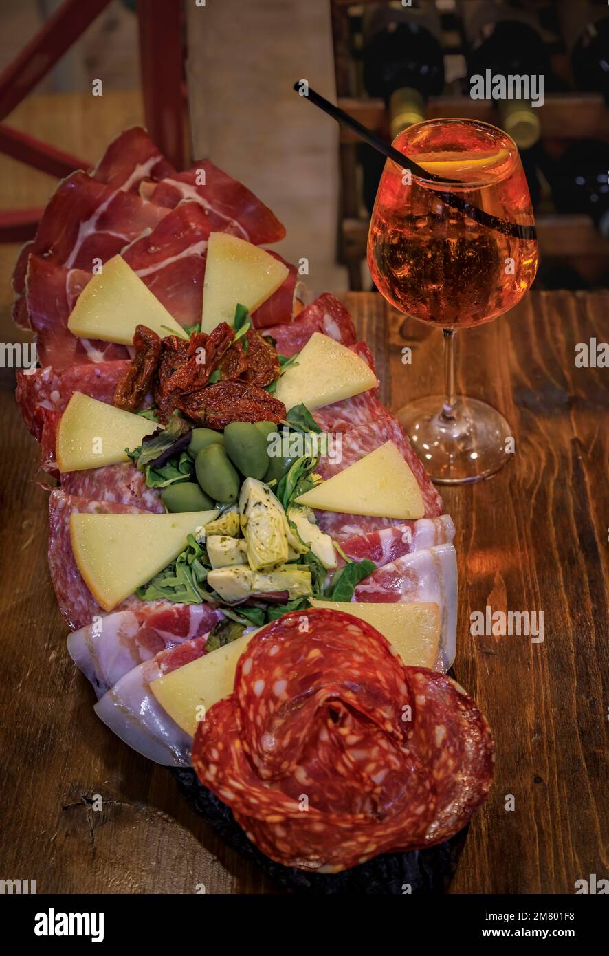 Italian antipasto platter with prosciutto, salami, cheese, olives served with a glass of aperol spritz cocktail at a restaurant in Florence, Italy Stock Photo