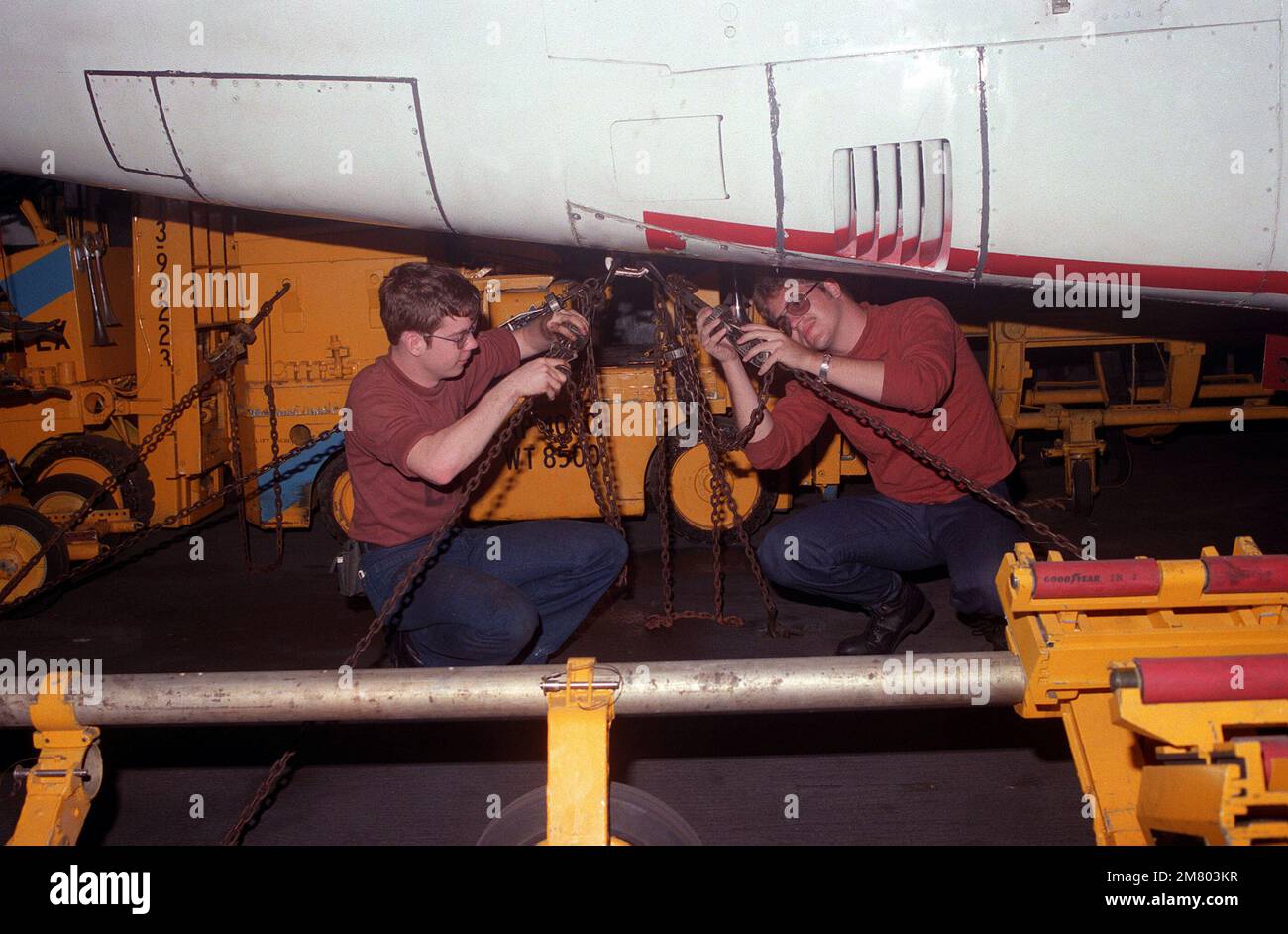 Maintenance crew members secure tiedown chains on an S3A Viking