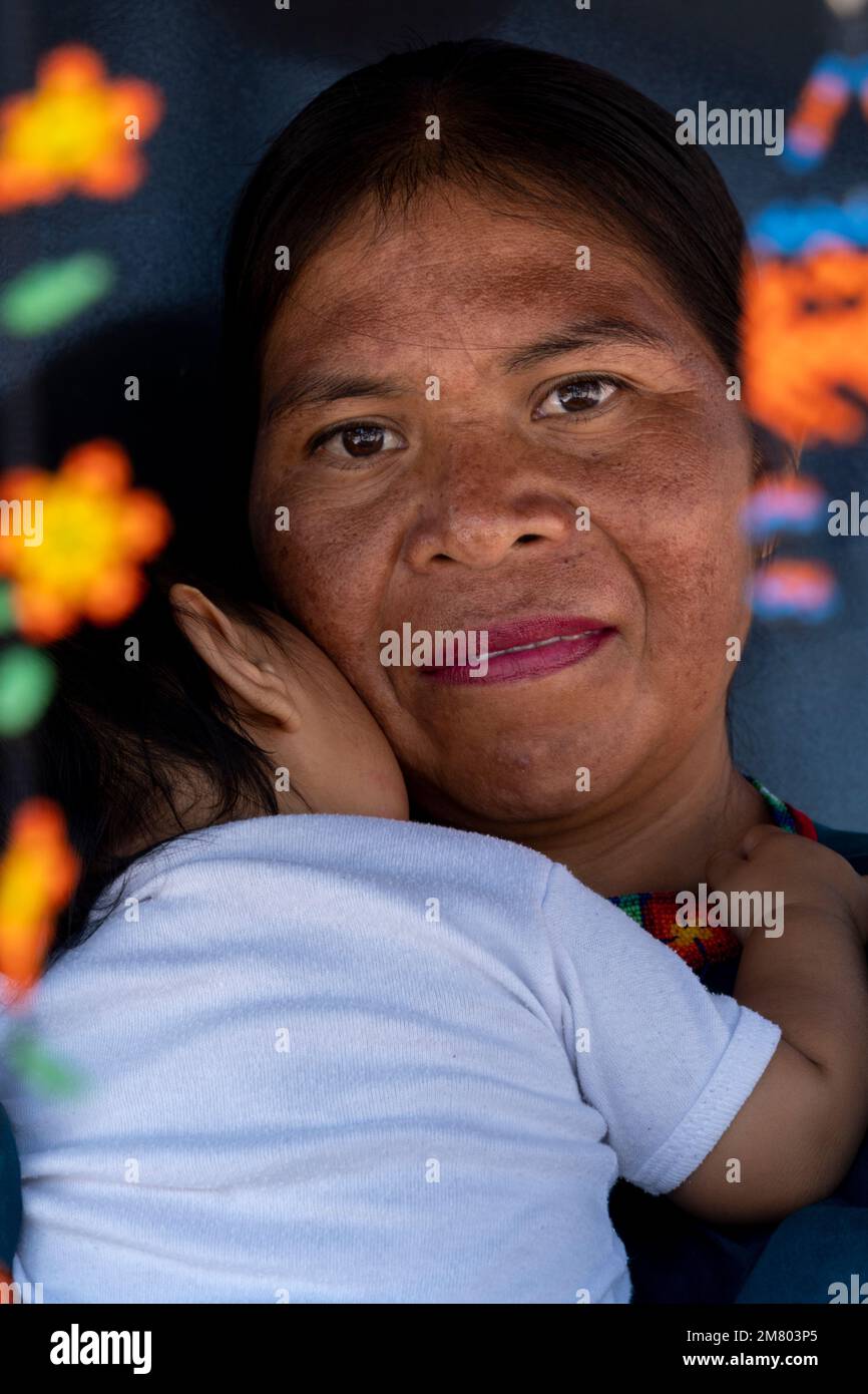 indigenous artisan woman with her newborn baby daughter with her handicraft hanging on her sides Stock Photo